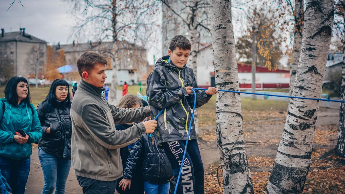 Kids enjoying an outdoor rope activity among birch trees during fall.
